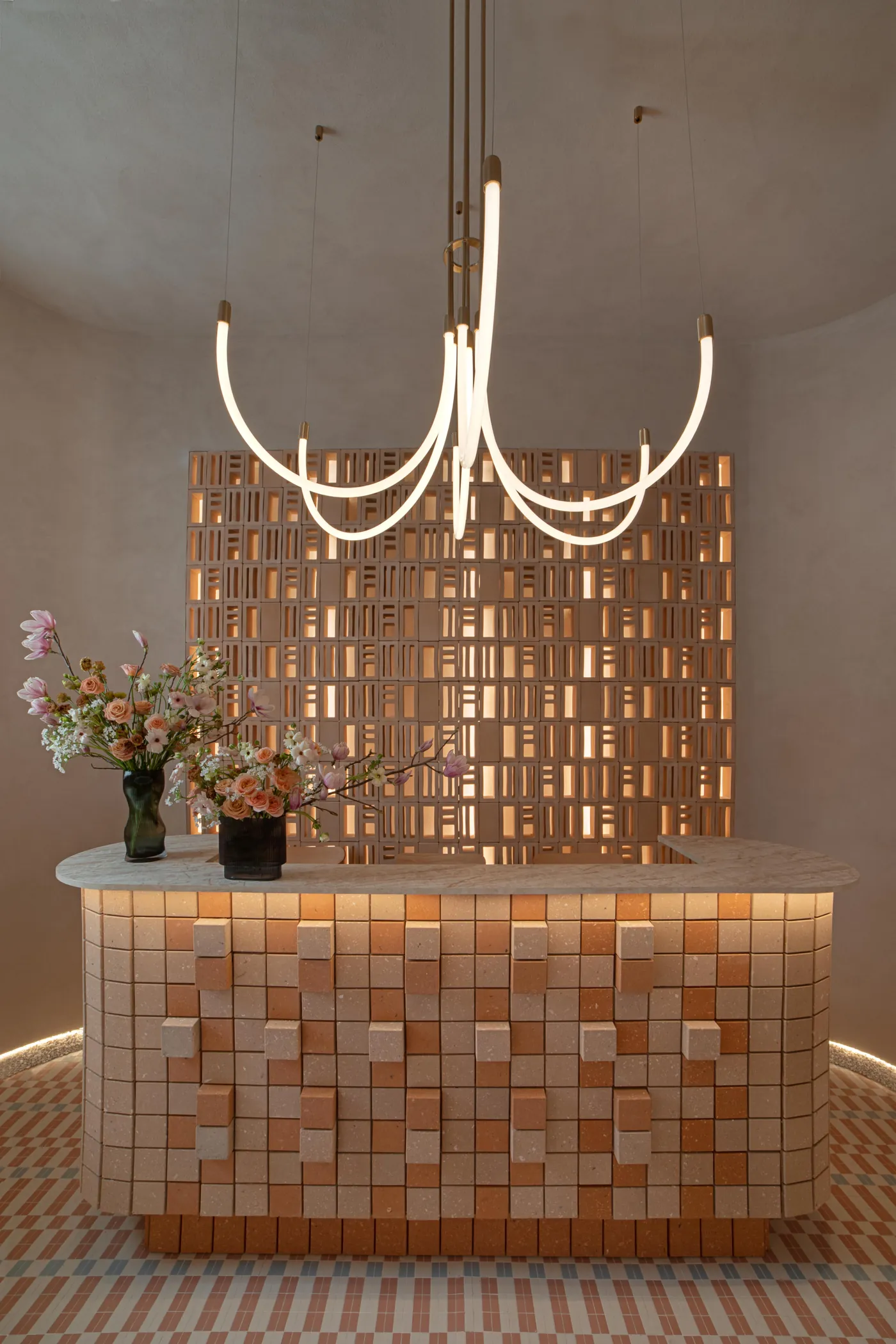 Glowing orange Manhattan panels on a reception counter and screen under a sculptural light