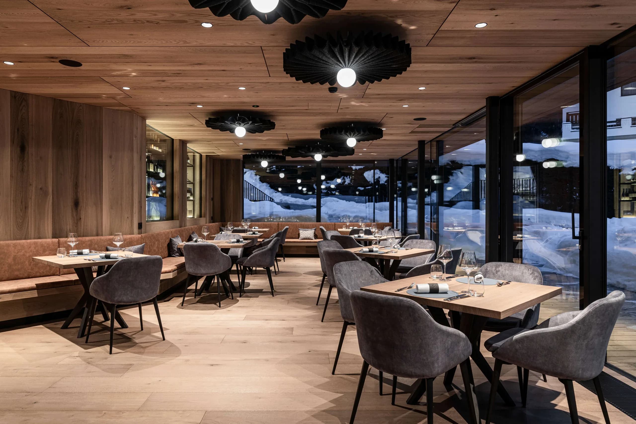 Upholstered dining chairs and tables in a timber-lined restaurant at Hotel Linder