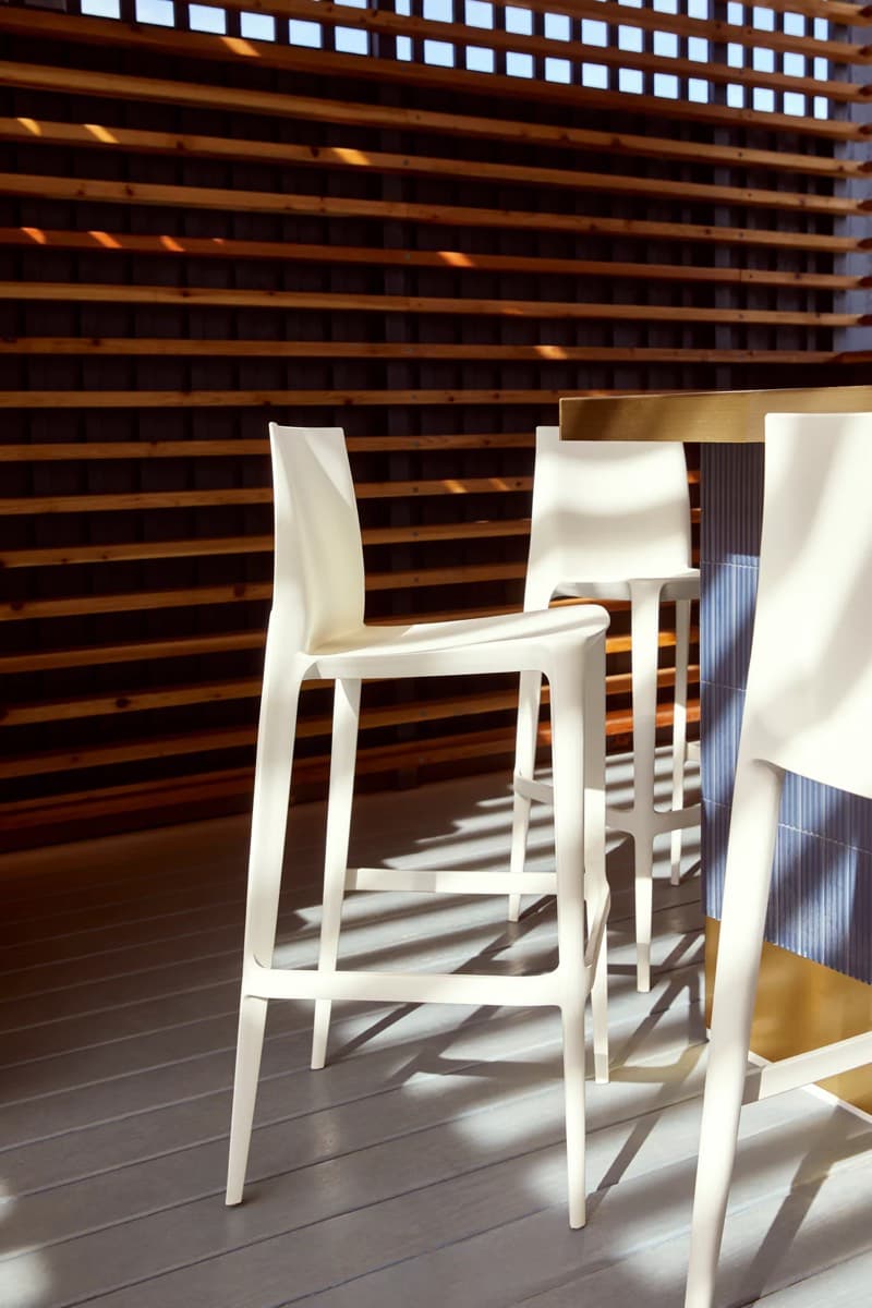 White Bellini bar stools at a sunlit counter against timber slats