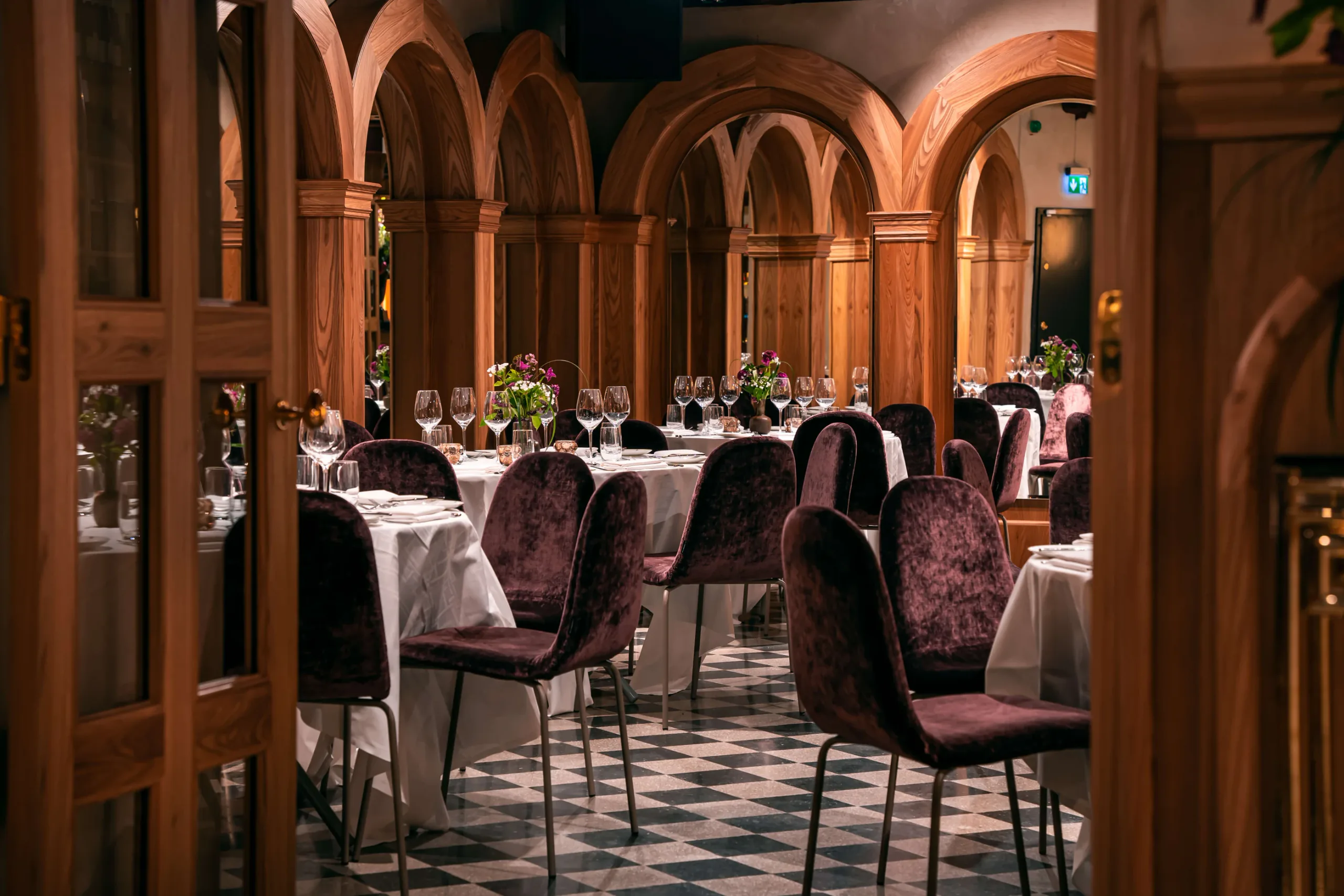 Plum velvet Mobliberica chairs at white-clothed tables under timber arches at Bank Hotel, Stockholm