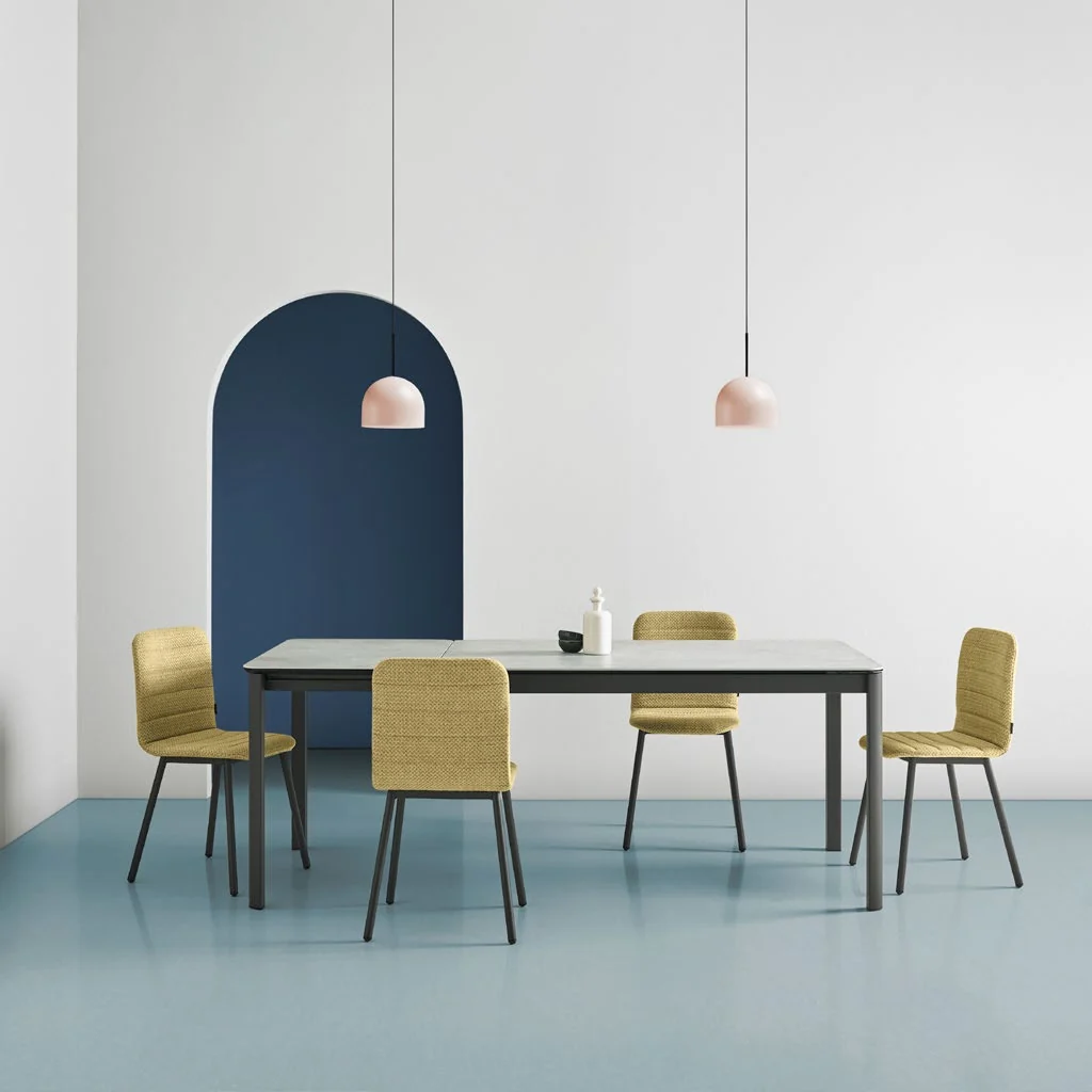 Yellow Pepper chairs around a grey ceramic table in front of a navy arch