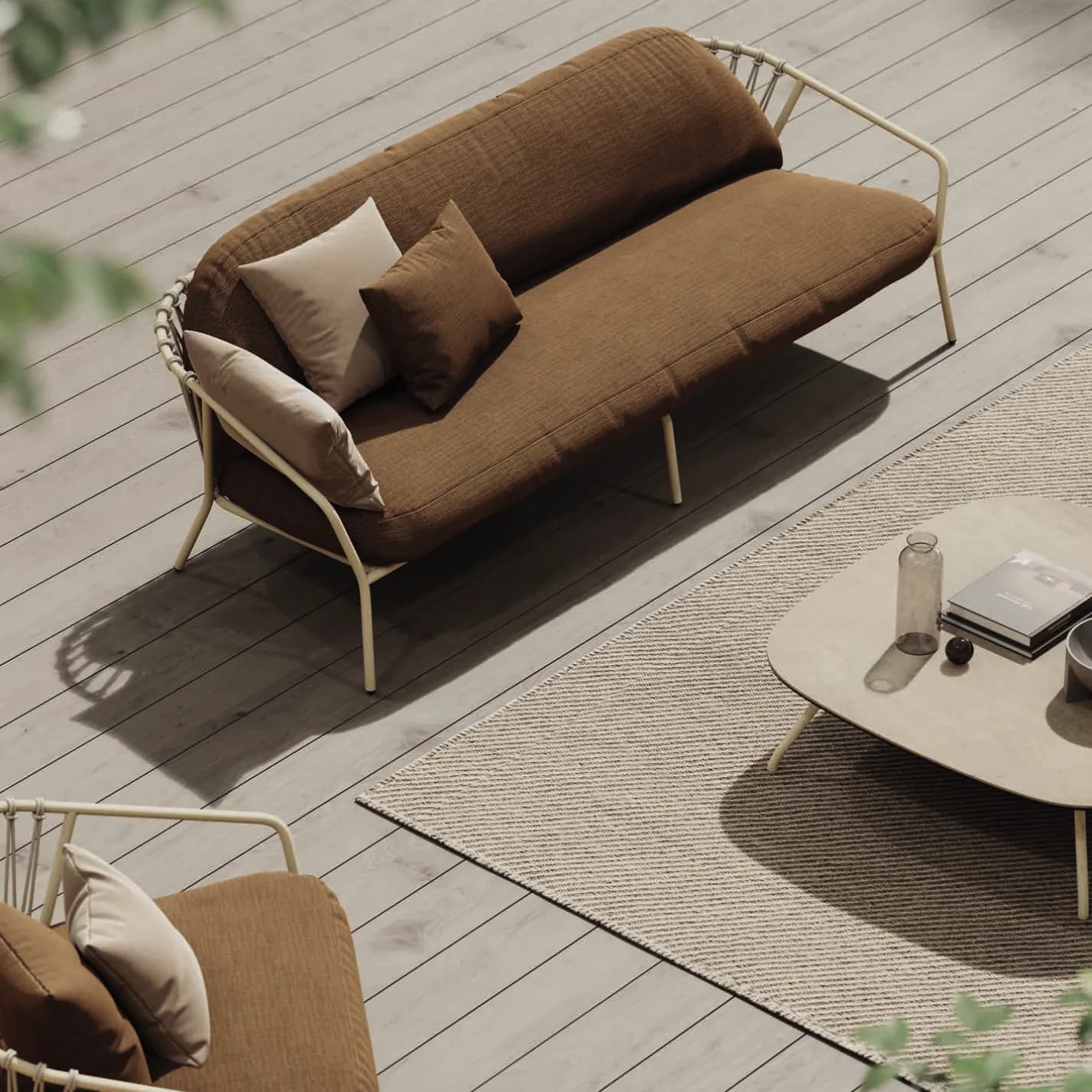 A Baga sofa with a rope back and rust cushions on a timber deck